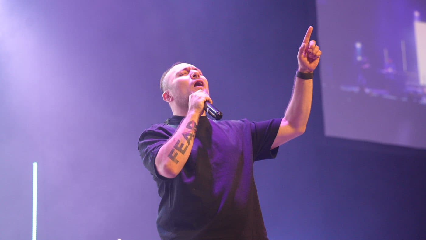 Tony Rosher cantando con el brazo levantado bajo luces moradas