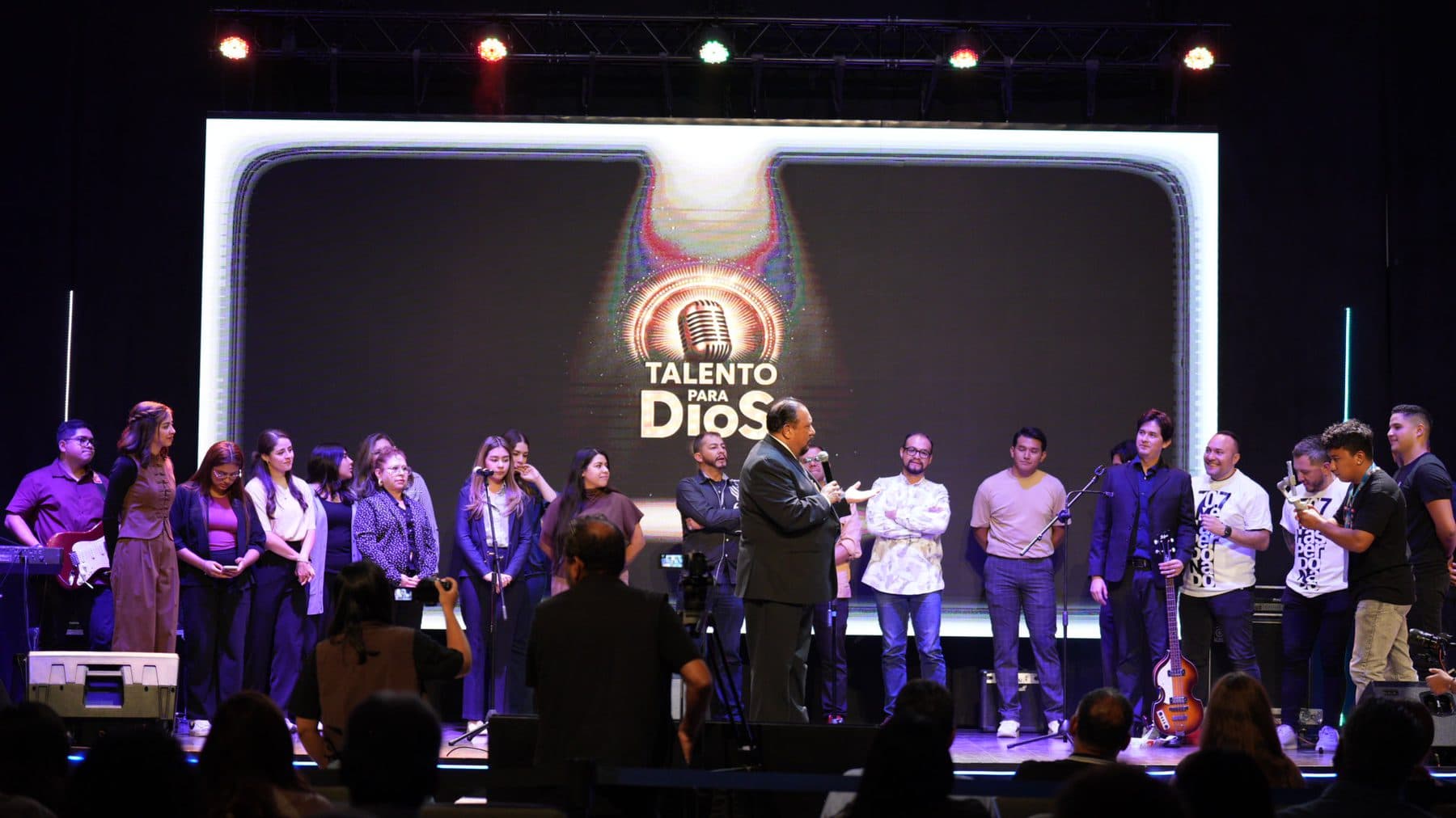 Todos los artistas y participantes reunidos en el escenario, frente al logotipo de Talento para Dios