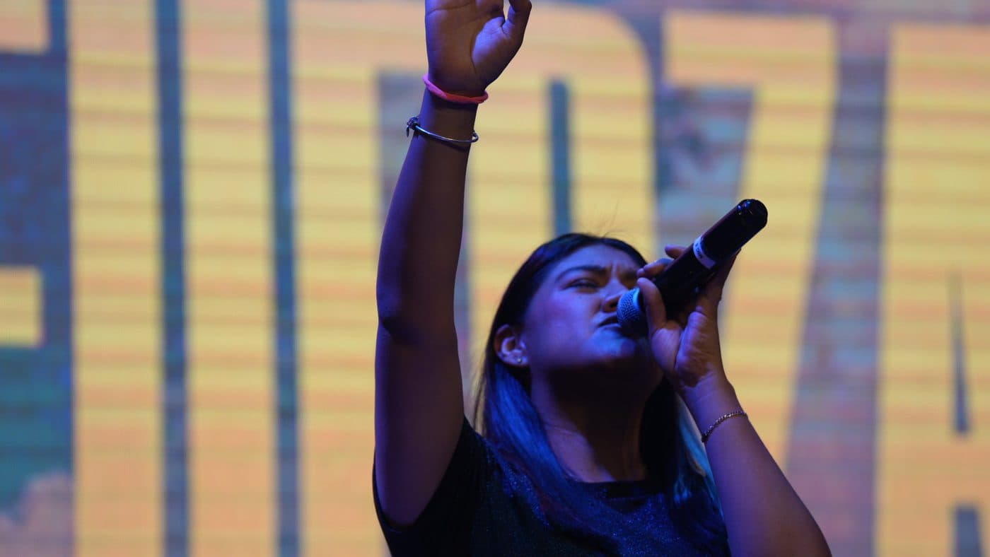 Una vocalista de Dfive cantando con el brazo en alto